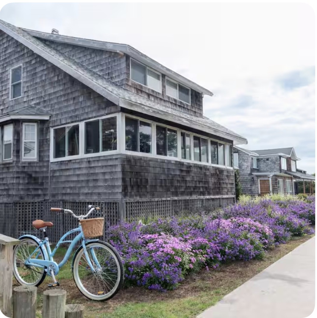 Cedar-shingled house with purple flowers and a blue bicycle